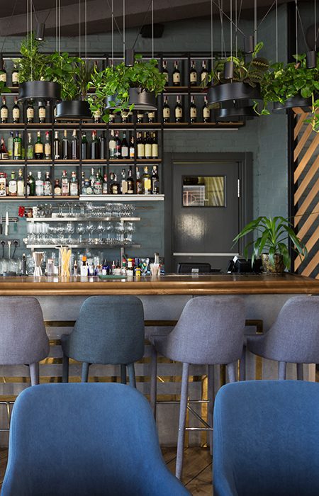 Inside a bar in River North Chicago with alcohol on shelves and a barter with empty chairs.