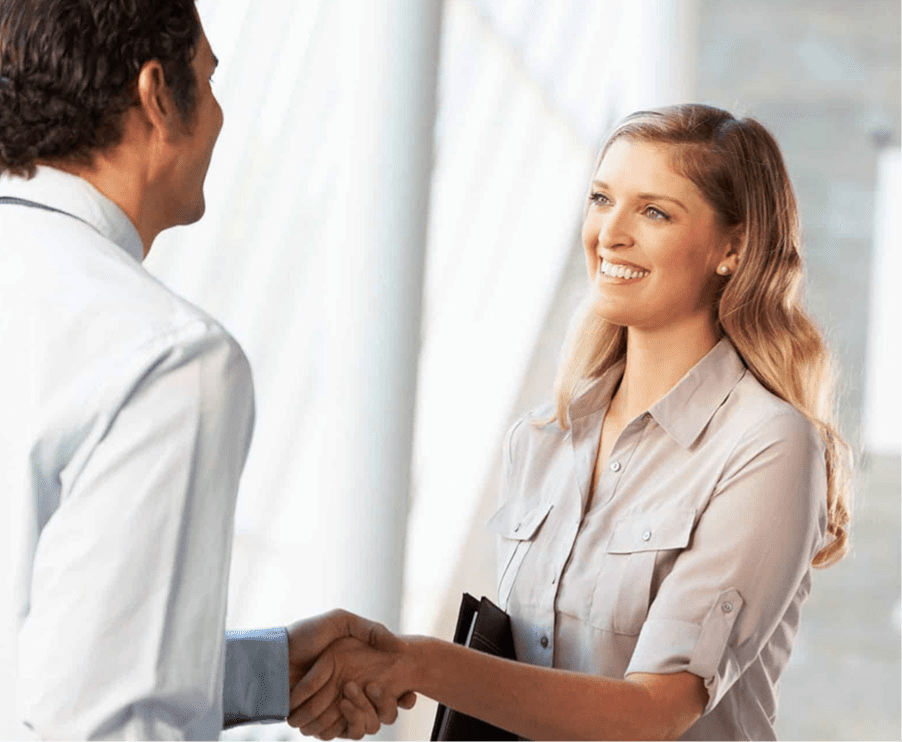 Male client meeting female apartment rental agent and shaking hands.